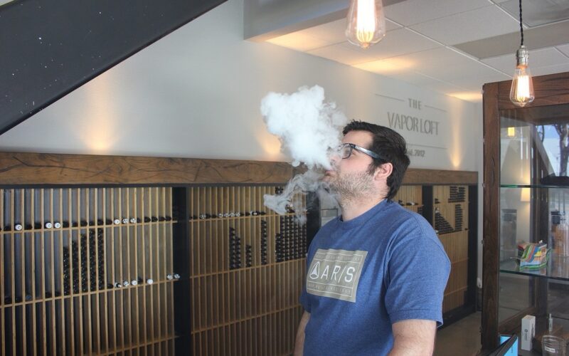 Vape shop interior with e-cigarette displays and an adult customer vaping