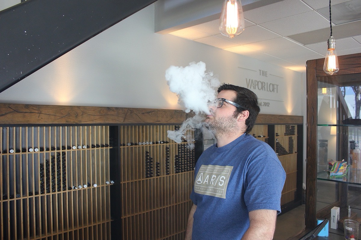 Vape shop interior with e-cigarette displays and an adult customer vaping