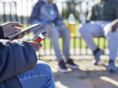 Teen holding a vape outdoors, used for coverage of the UK consultation on vape packaging, flavour names and retail display rules